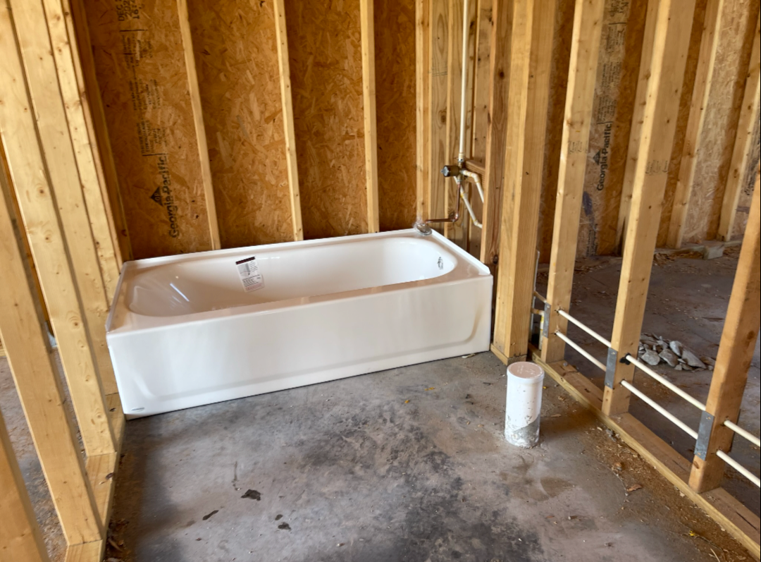 New bathtub set in framed bathroom with drain stub-up ready for finish work